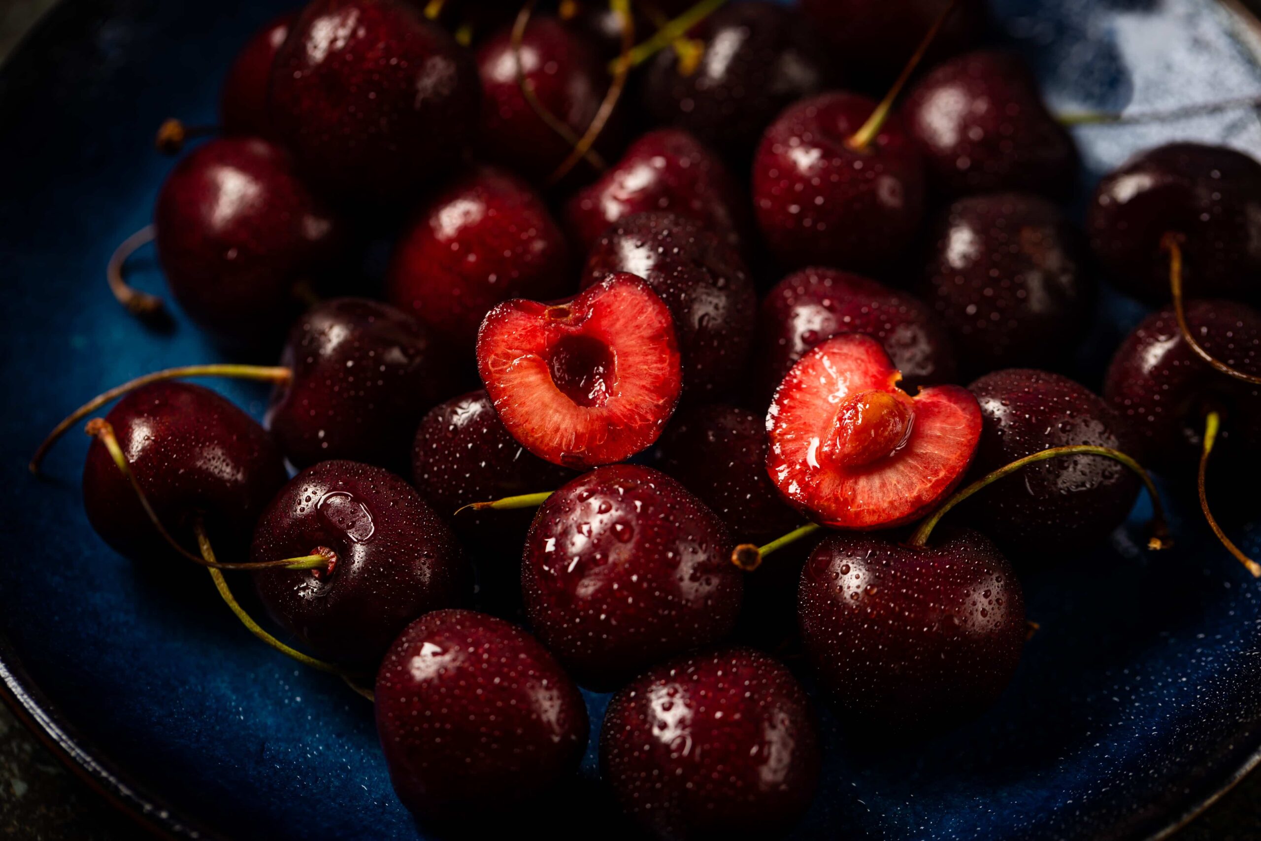 Cerezas frescas en primer plano con dos mitades cortadas — campaña de cerezas Chile 2025/26 y proyección de cosecha récord.